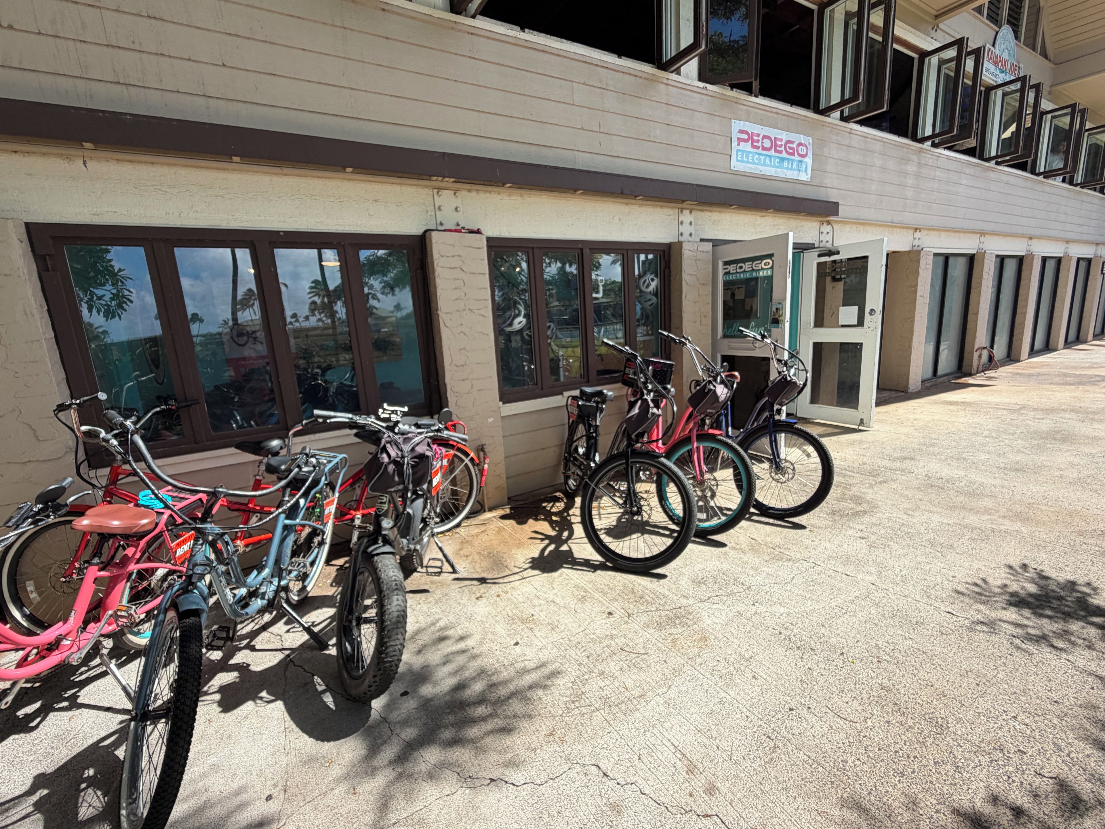 A building with a sign for 'PEDEGO ELECTRIC BIKE' and several bicycles parked outside.