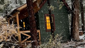 A cabin with a wooden deck and a window with a yellow glow. - Lakeshore Resort (Lakeshore)