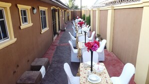 Un couloir avec des tables et des chaises, chacune étant recouverte d’une nappe blanche et agrémentée de fleurs rouges.