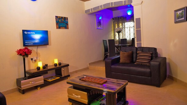 Un salon comprenant un téléviseur, un canapé, une table basse et un coin repas avec une fenêtre.