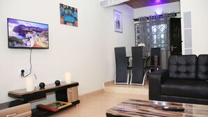 Un salon comprenant un téléviseur, un canapé en cuir noir, une table basse et un meuble pour téléviseur agrémenté d’objets décoratifs.