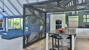 A modern kitchen with a central island, bar stools, and a decorative screen. - Unique luxuous 350sq m Villa with pool, fitness area, home cinema lounge .... (bora bora)