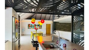 A modern kitchen with a central island, a sink, and a dining area with yellow chairs. - Unique luxuous 350sq m Villa with pool, fitness area, home cinema lounge .... (bora bora)