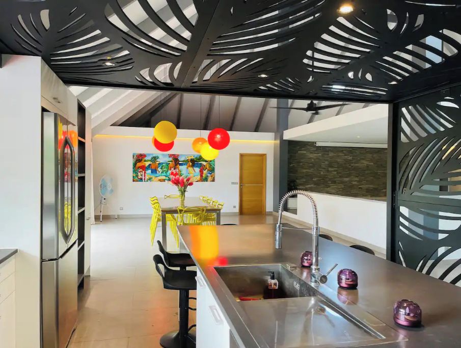 Une cuisine moderne dotée d’un îlot central, d’un évier et d’un coin repas avec des chaises jaunes.