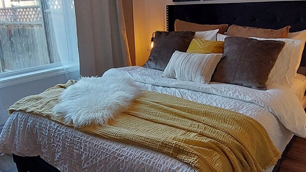 A bedroom with a bed, a window, and a ceiling light. - Cozy basement suite near the mountains (Cochrane)