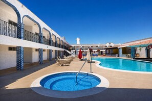 A pool area with lounge chairs and umbrellas, a clear sky, and a building with blue and white walls. - Playa Inn Rocky Point (Puerto Peñasco)