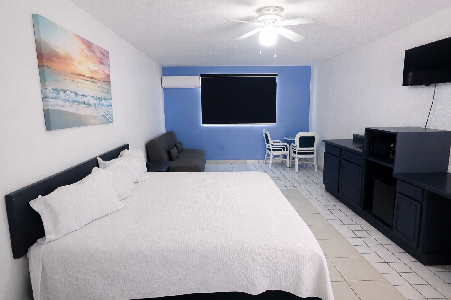 A bedroom with a bed, a TV, a desk, and a chair.
