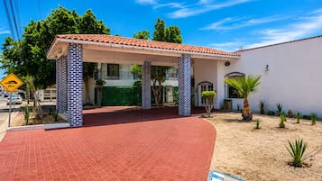 Un edificio con techo de tejas rojas, fachada de ladrillo y un área de entrada cubierta.