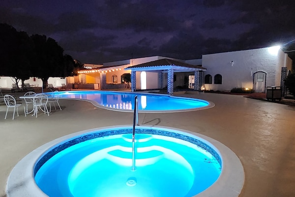 Een buitenzwembad, parasols bij het zwembad en ligstoelen