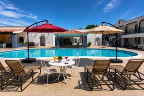 A swimming pool with lounge chairs and umbrellas, a restroom, and a covered seating area. - Playa Inn Rocky Point (Puerto Peñasco)