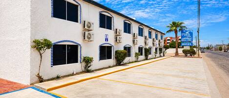 A hotel with a row of rooms, air conditioning units, and a sign for Playa Inn Rocky Point Hotel.