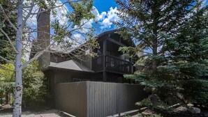 A two-story building with a balcony, surrounded by trees and a wooden fence.
