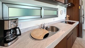A modern kitchen with stainless steel appliances, a built-in oven, and wooden cabinets. - 1 BR Condo w/ Ocean View Infinity Pool (Isla Mujeres)