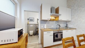 Eine kleine Küche mit weißen Schränken, einer Holz Arbeitsplatte, einem eingebauten Backofen und einem Spülbecken.