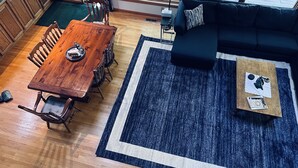 Un salon moderne avec une table à manger en bois, un canapé bleu foncé et un tapis bleu.
