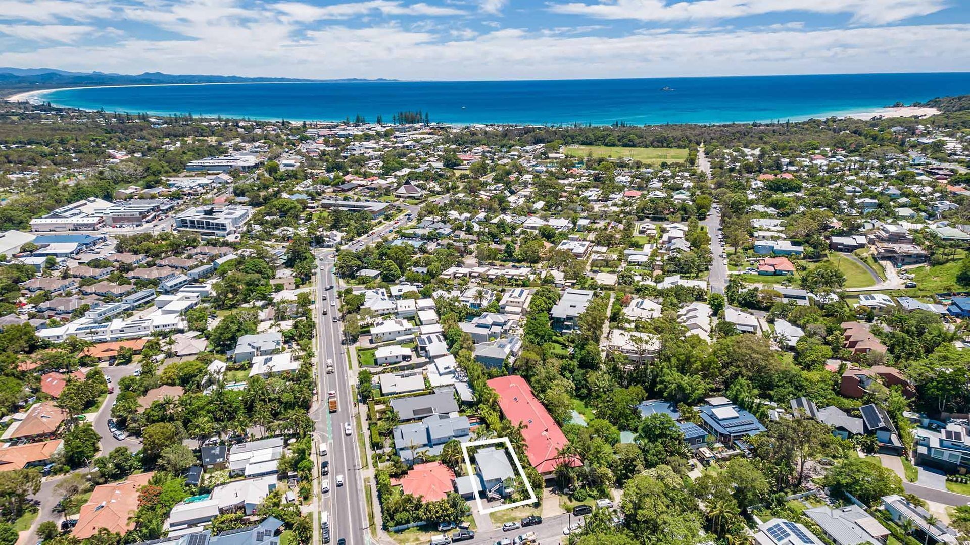A residential area with houses, roads, and a beach in the background.