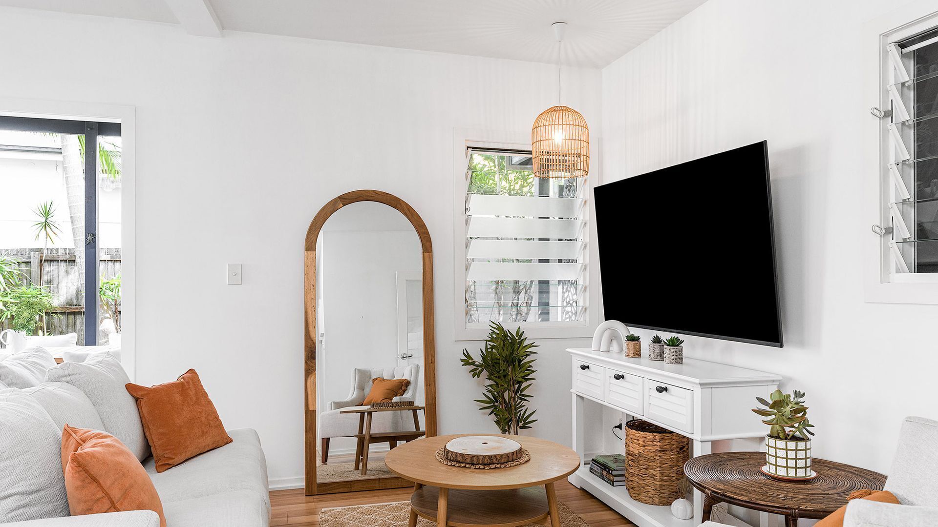 En moderne stue med sofa, sofabord og et fjernsyn ophængt på væggen.