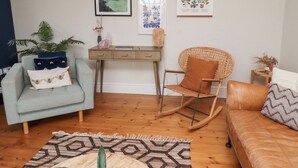 A living room with a light blue armchair, a rocking chair, a wooden desk, and a patterned rug. - Rosedale Lodge (Alnwick)