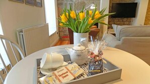 Ein Esstisch mit einer Tablettgarnitur, bestehend aus einem Teekessel, Tassen, einer Brokasten und einer Vase mit gelben Blumen.