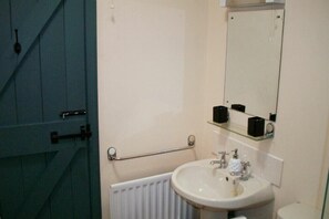 A bathroom with a white sink, a mirror, and a towel rack. - Swallow Cottage (Alnwick)