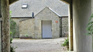 A stone building with a door, under an archway. - Swallow Cottage (Alnwick)