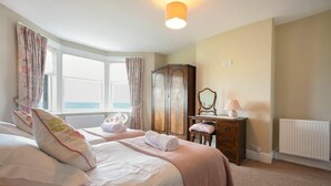 Un dormitorio con dos camas, un aparador, un espejo y una ventana con cortinas.