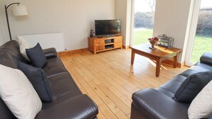 Ein Wohnzimmer mit einer Sofagarnitur, einem Fernseher auf einem Holzboden und einem Tisch mit Dekorationen.