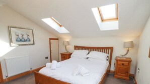 Ein Schlafzimmer mit einem hölzernen Bett, zwei Nachttischen, einer Heizung und Dachfenstern.