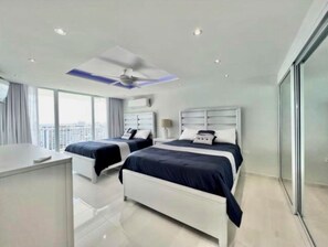 Two single beds with bedside tables and lamps, offering a city view from the large window.