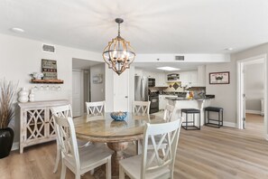 A spacious kitchen with white cabinets, a central island, and a dining area with a round table and white chairs.