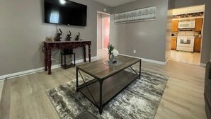 A living room with a flat-screen TV, a coffee table, and a dining table with chairs. - Home in Liberty (Liberty)