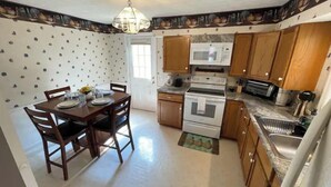A compact kitchen with wooden cabinets, a microwave, an oven, and a sink. - Home in Liberty (Liberty)