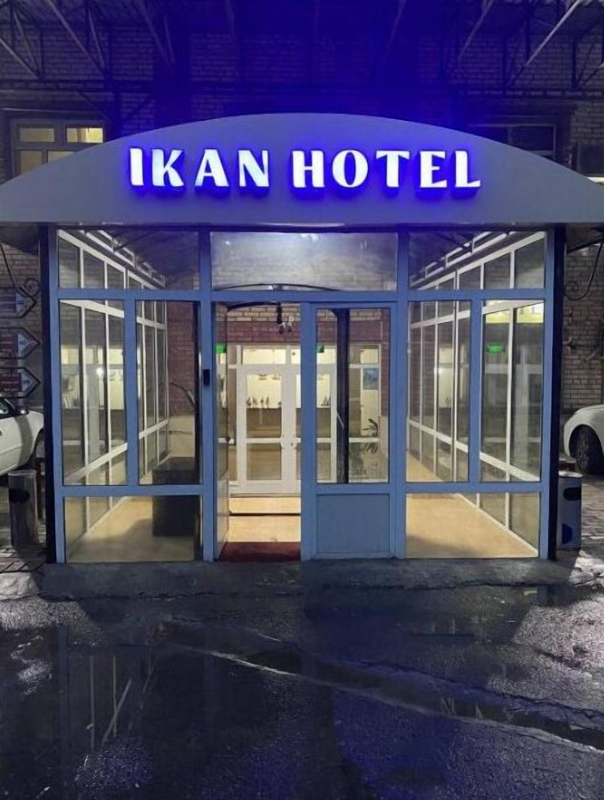 The exterior of Ikan Hotel with a glass entrance and a sign above.