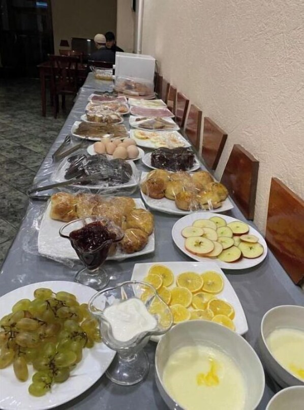 A buffet table with various dishes including fruits, bread, and a bowl of soup.