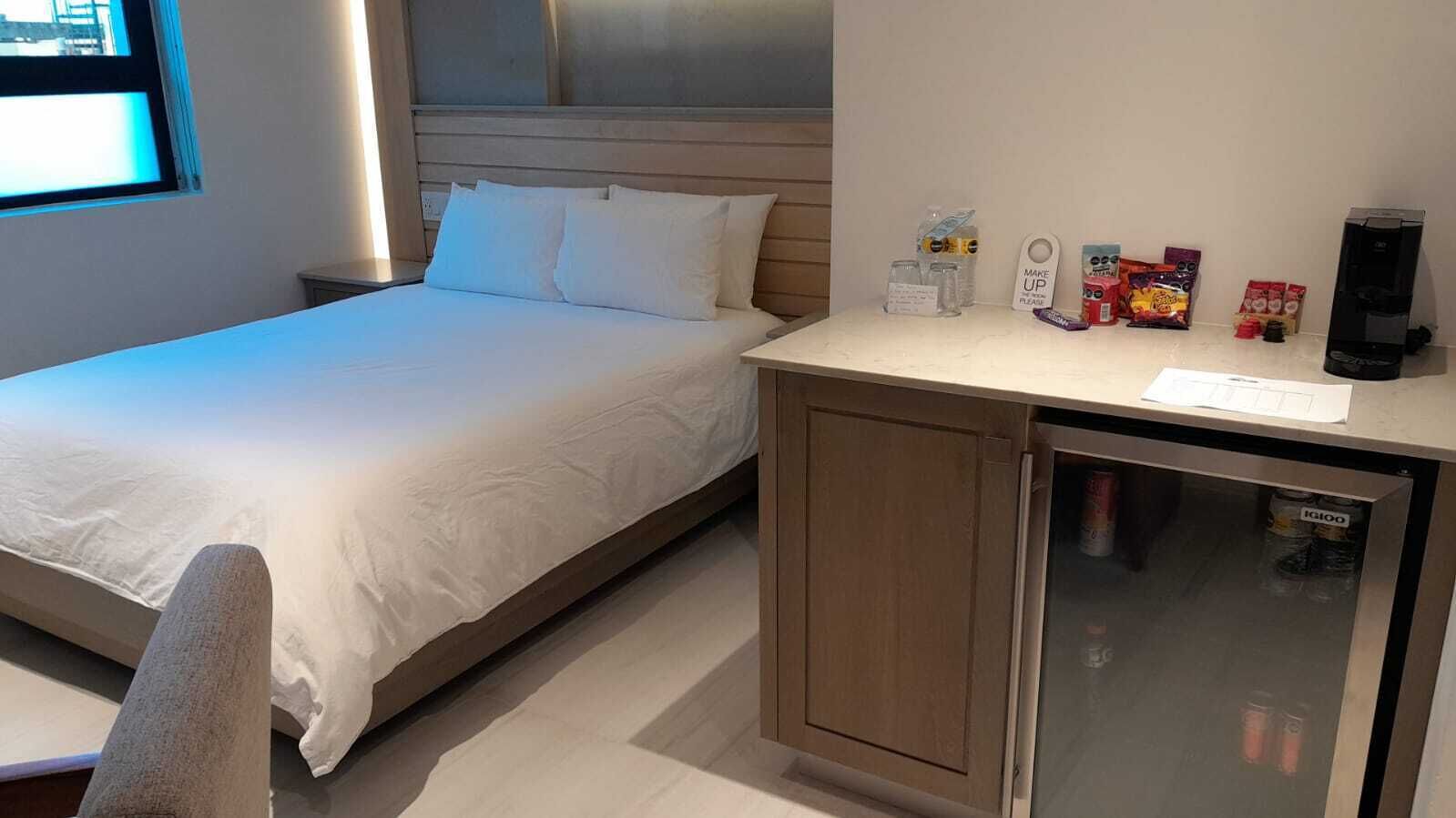 Une chambre d’hôtel avec un lit, une petite kitchenette et un réfrigérateur.
