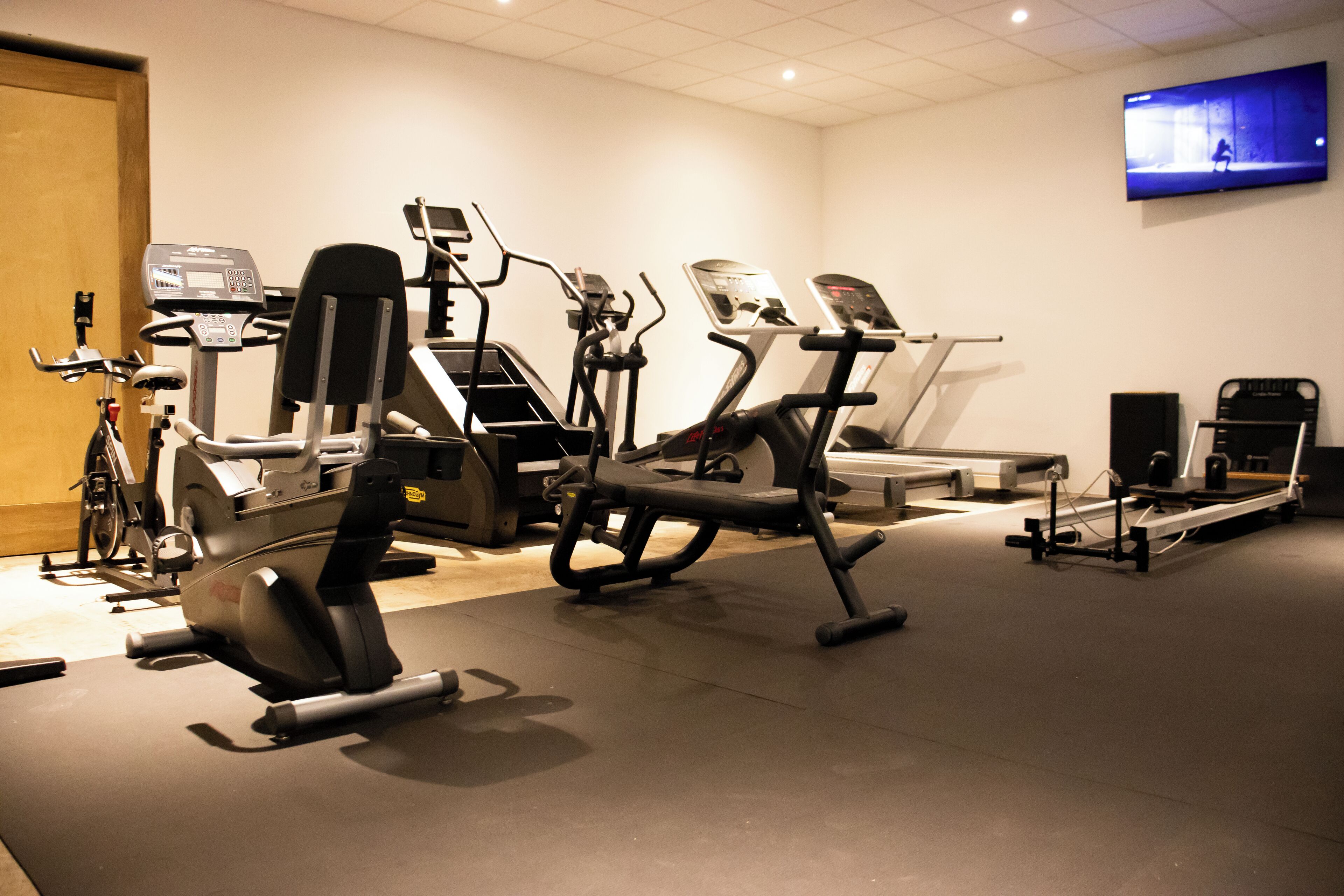 A gym with various exercise equipment including treadmills, elliptical machines, and a stationary bike.