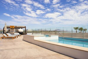 Ein Pool auf dem Dach mit Liegestühlen und einer Grillgegend.