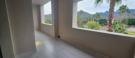 A spacious room with large windows offering a view of palm trees and mountains.
