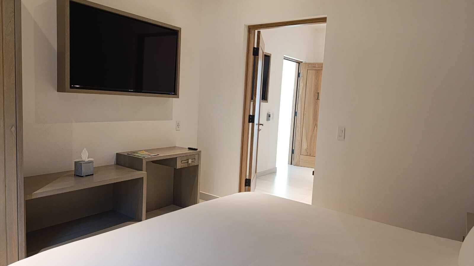 A minimalist room with a bed, a desk, and a large window.