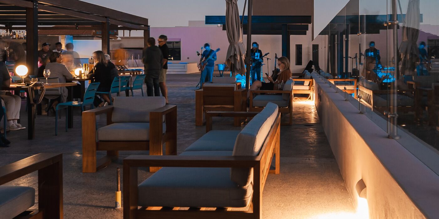 Un área de estar al aire libre con mobiliario de madera y un escenario para música en vivo.