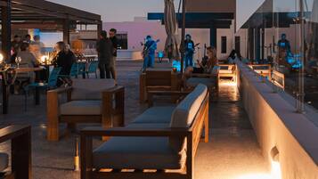 Un área de estar al aire libre con mobiliario de madera y un escenario para música en vivo.