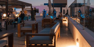 Un área de estar al aire libre con mobiliario de madera y un escenario para música en vivo.