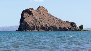 A beach with a large rock formation in the water. - Aventuras Hotel (Loreto)