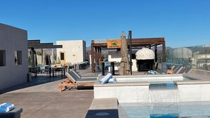 A rooftop pool area with lounge chairs, a barbecue, and a view of the mountains. - Aventuras Hotel (Loreto)