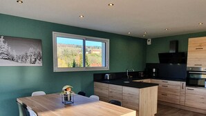 Una cocina moderna con armarios de madera, encimera negra y ventana con vistas a árboles y edificios.