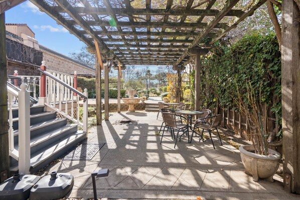Relax in a shaded patio area with a pergola, comfortable seating, and a small table for dining or socializing.