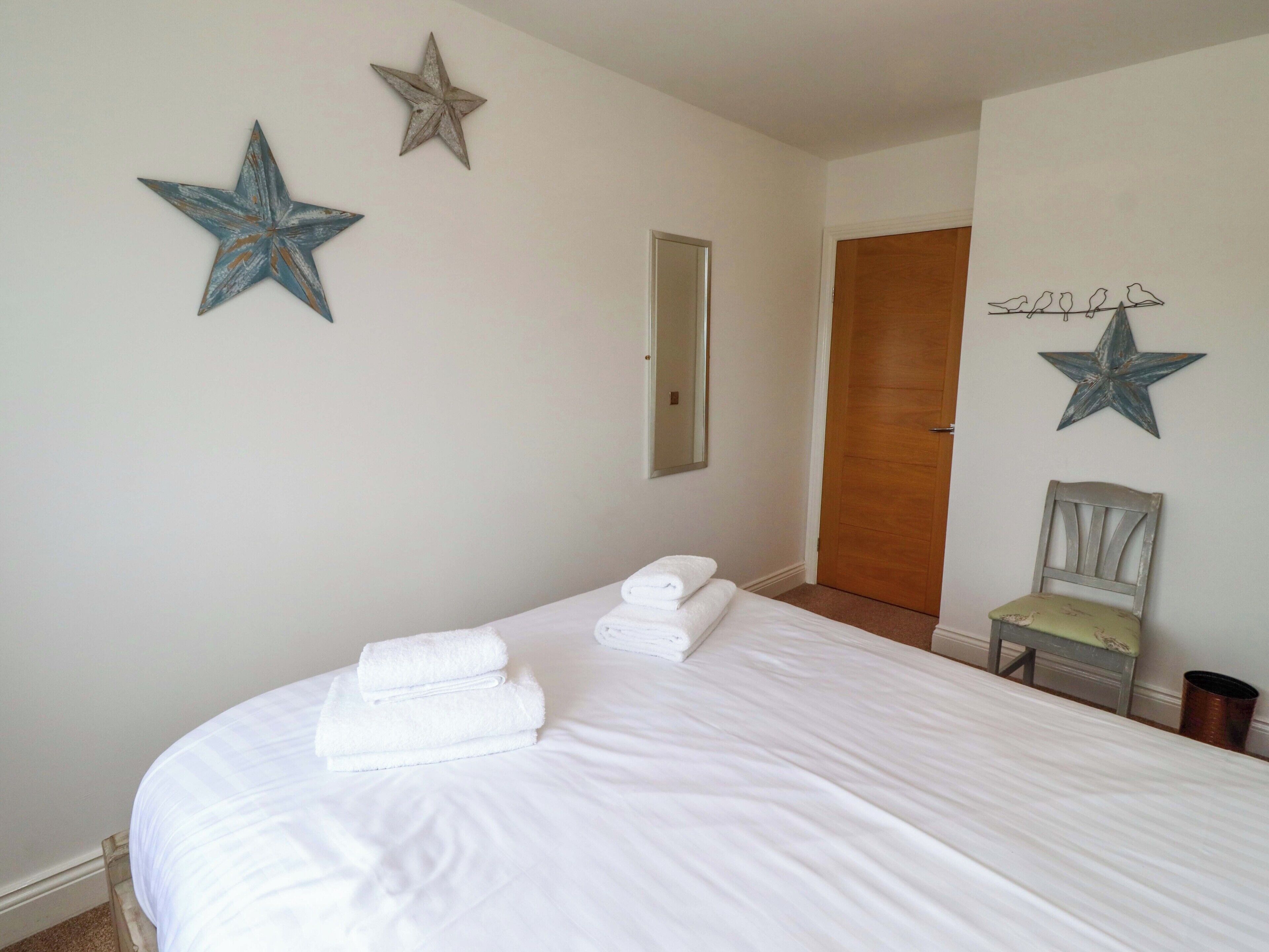 A bedroom with a bed, two stars on the wall, a chair, and a door.