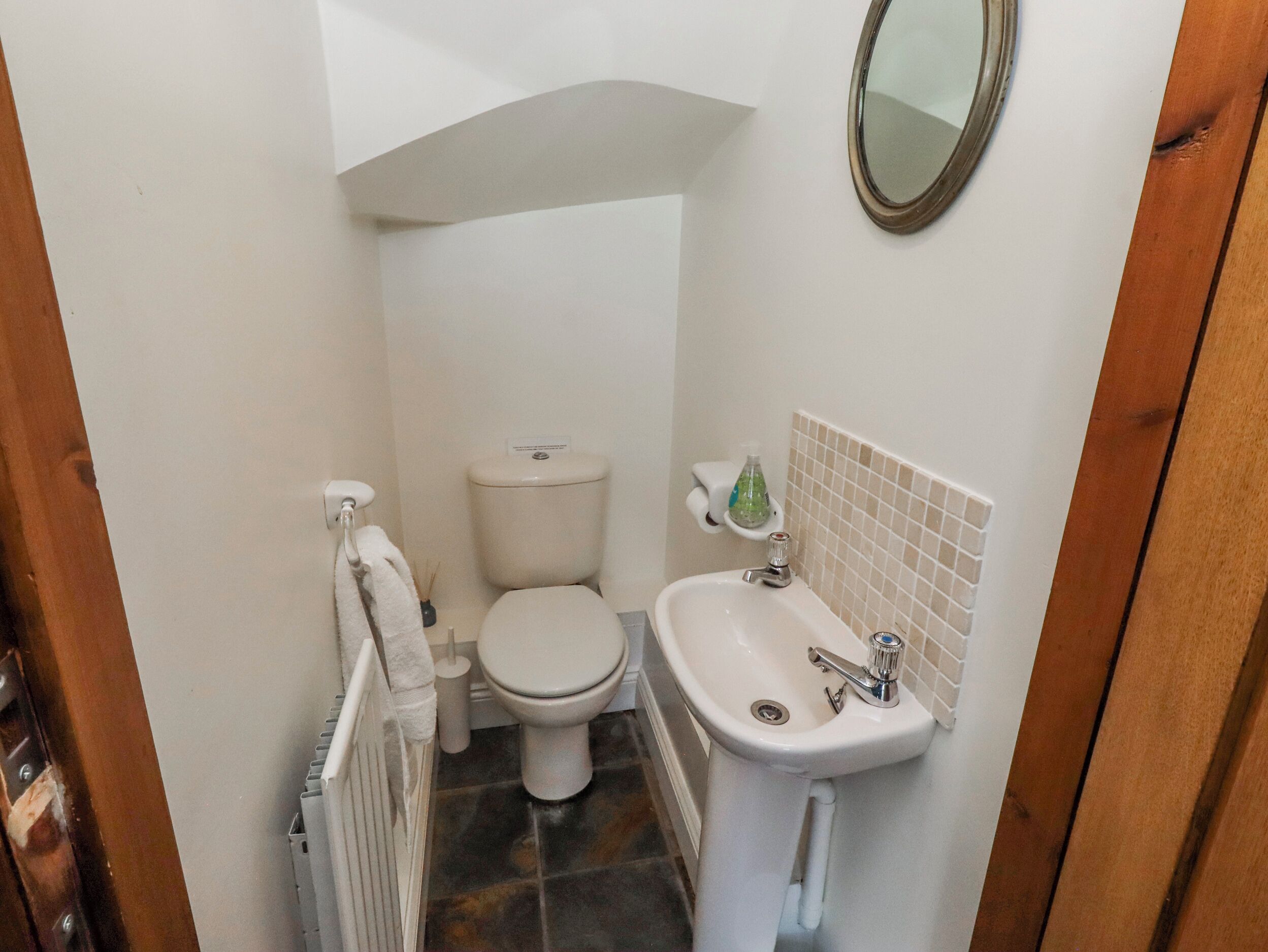 A compact bathroom with a toilet, sink, and mirror.