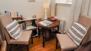 A cozy room with two chairs, a small table, a lamp, a bookshelf, and a window with curtains. - No9 Budle Sands (Bamburgh)