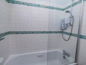 Ett badrum med vita kakelplattor, en dusch och ett badkar.